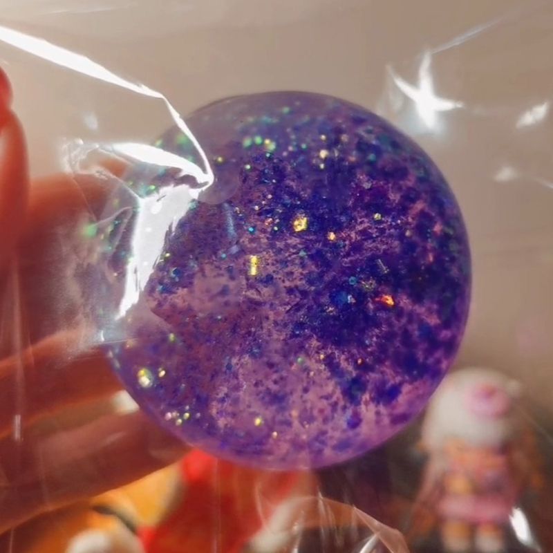 Aurora squishy ball squeezed in hand showing slow rebound